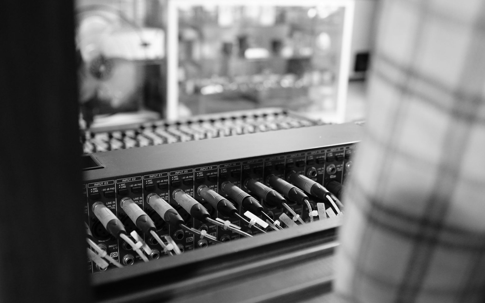 An adult broadcast engineer at a studio patch bay, cables and labelled ports in close frame